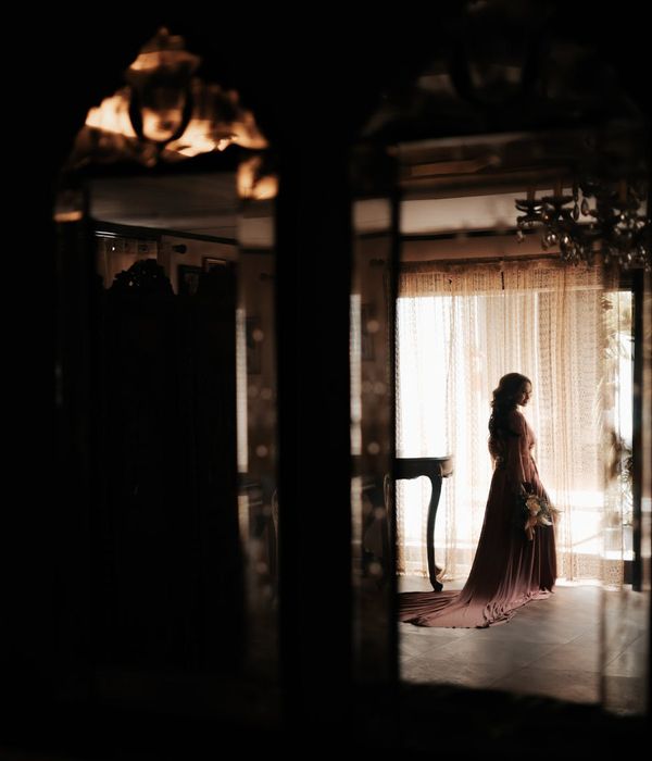 Woman in a serene yoga pose in a dark room with apricot colored light.